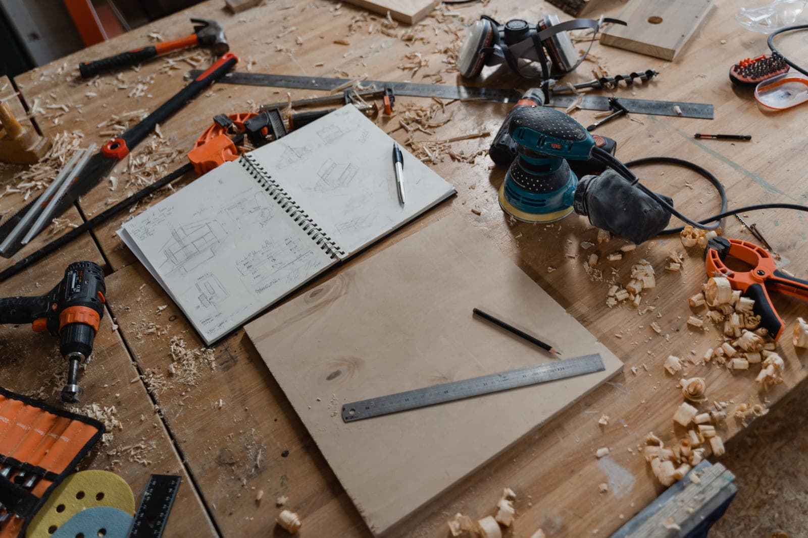 A workbench with a notebook, pencil and hand tools
