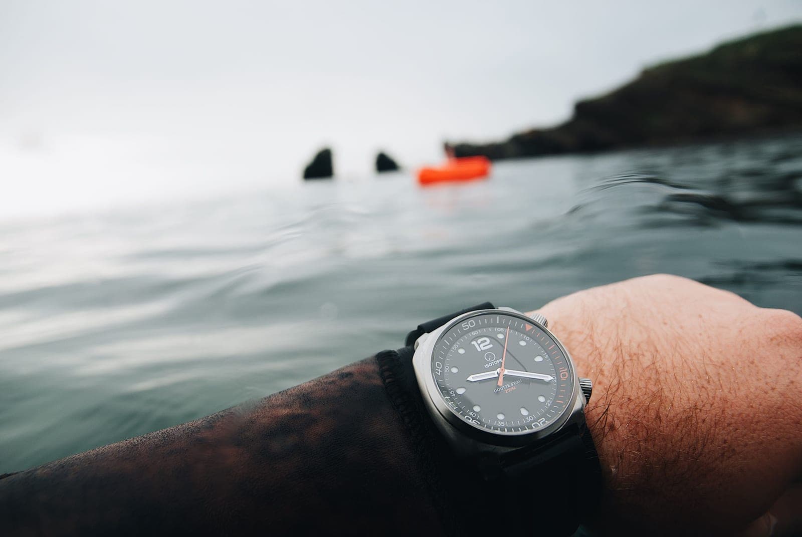 A diver's wristwatch resting on a wet dark surface