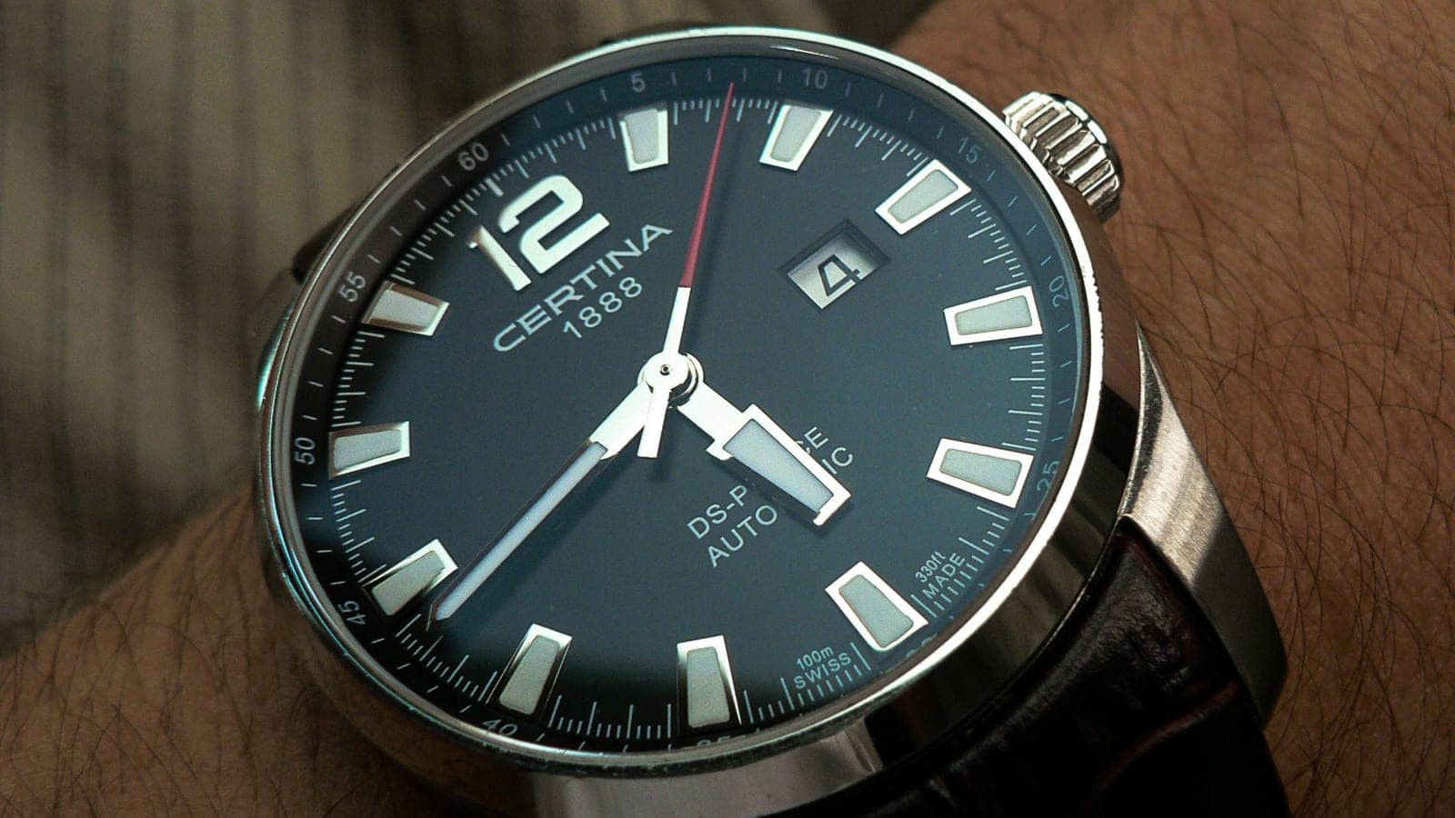 A scratched steel watch case photographed close up