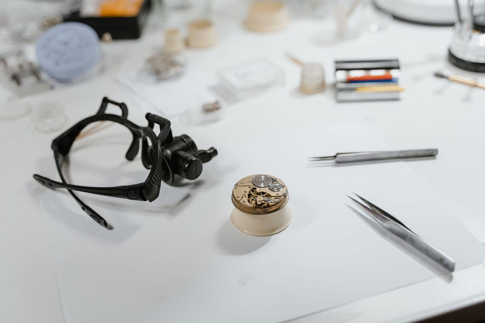 A watchmaker's loupe resting beside a movement on a bench