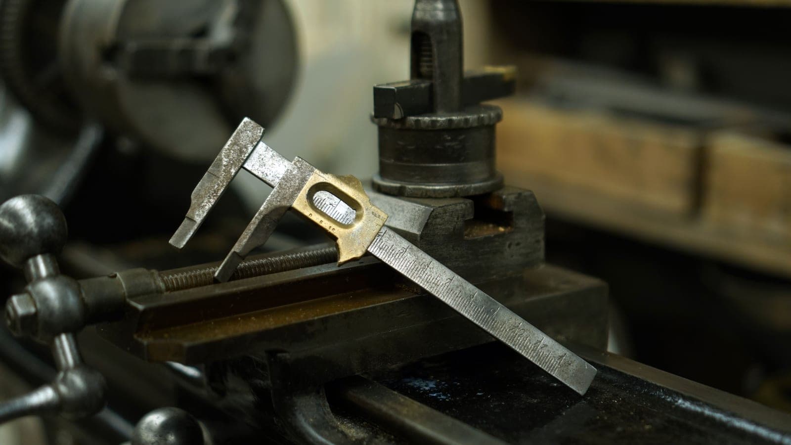 A caliper measuring a machined metal part on a workbench