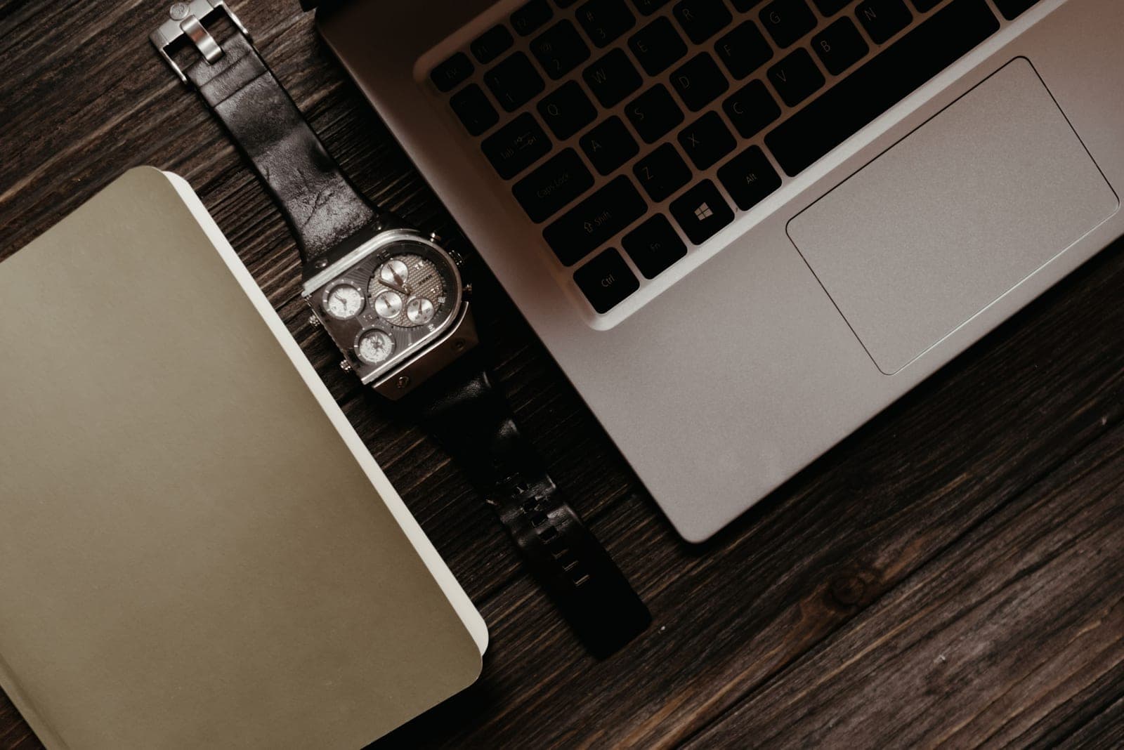 A desk with a wristwatch and an open notebook