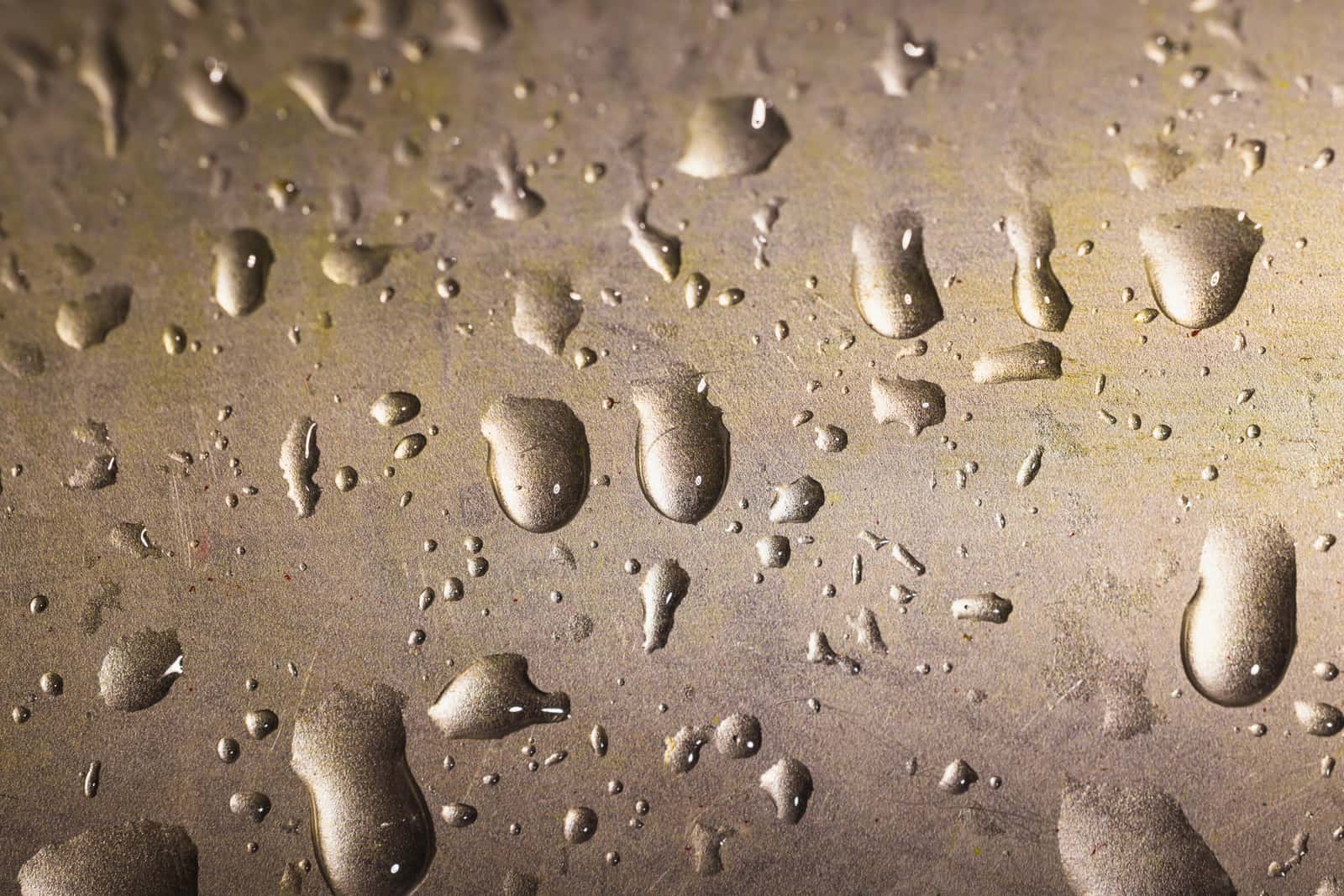 Water droplets beaded on a brushed metal surface